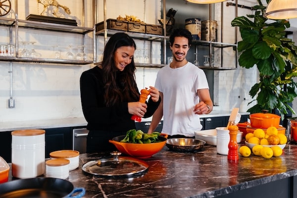 couple in kitchen smiling & cooking