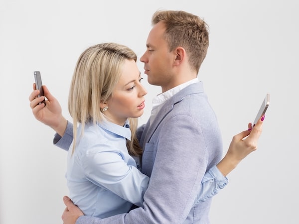 couple holding each other on phones